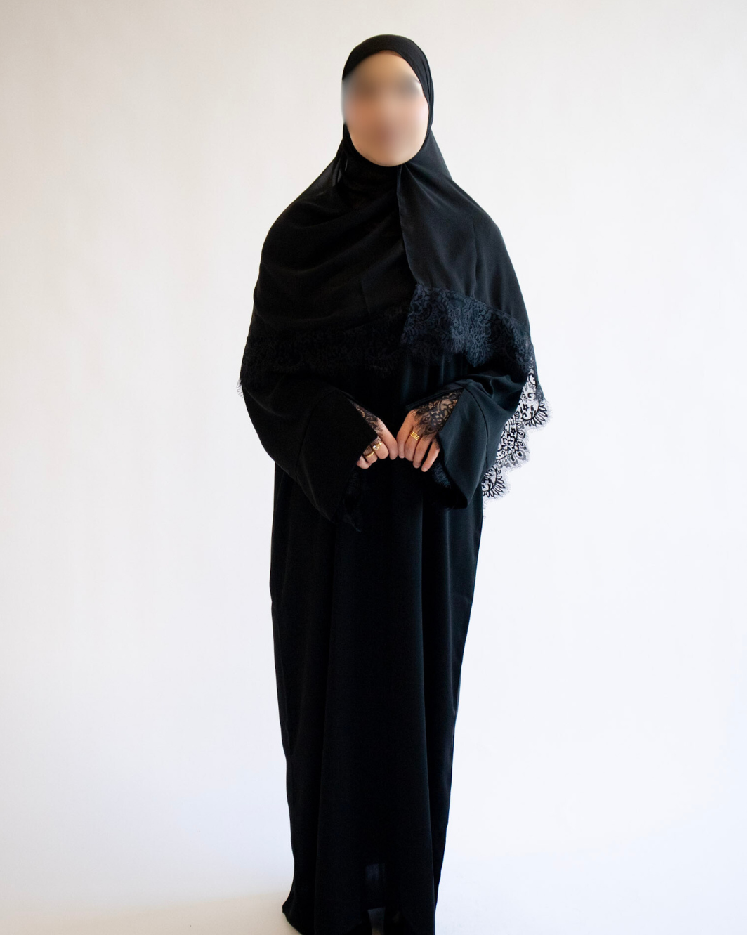 Person wearing a black abaya with floral embroidery on a white background